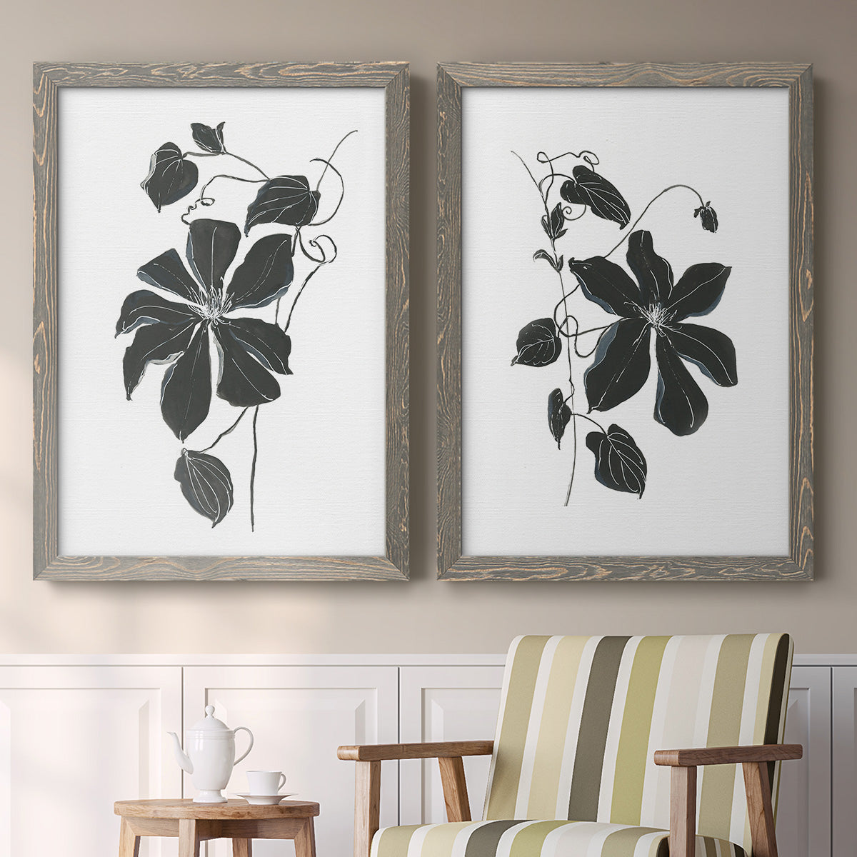 Set of two gray barnwood framed canvas prints depicting two minimalist botanical prints featuring black leafy vine silhouettes above a sideboard in a cozy sitting room.