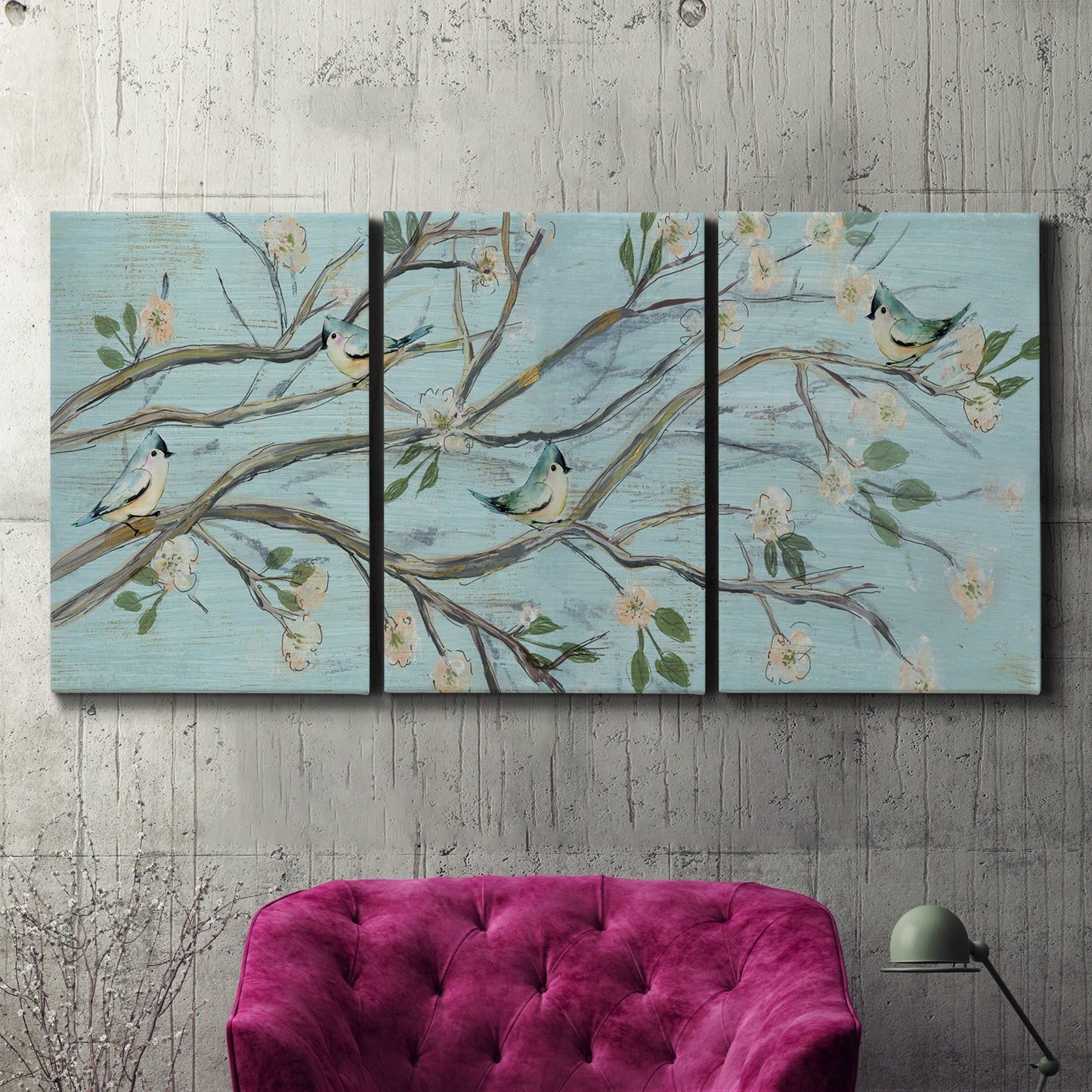 Three-panel canvas wall art featuring blue sky with flowering branches, displayed in a living room above a suede accent chair.