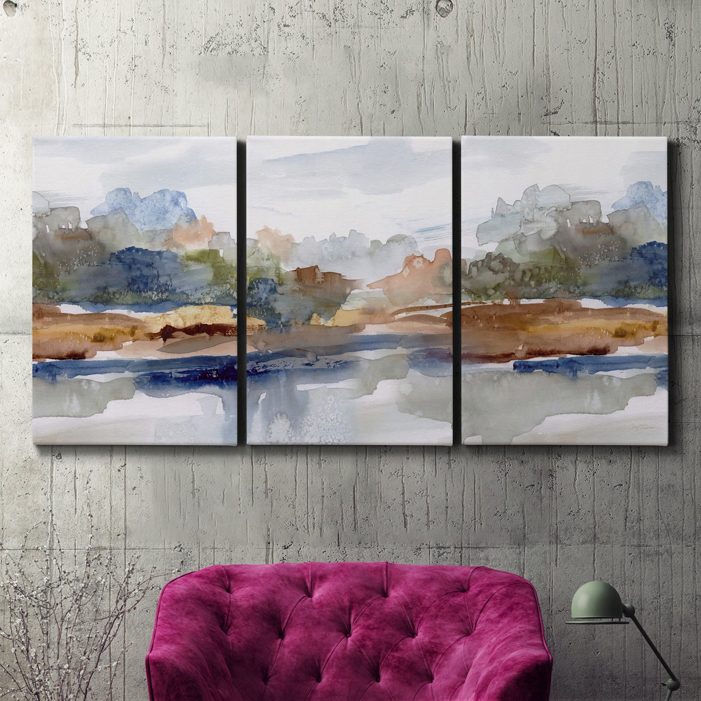 Three-panel canvas wall art featuring layered abstract mountain forms, displayed in a living room above a suede accent chair.