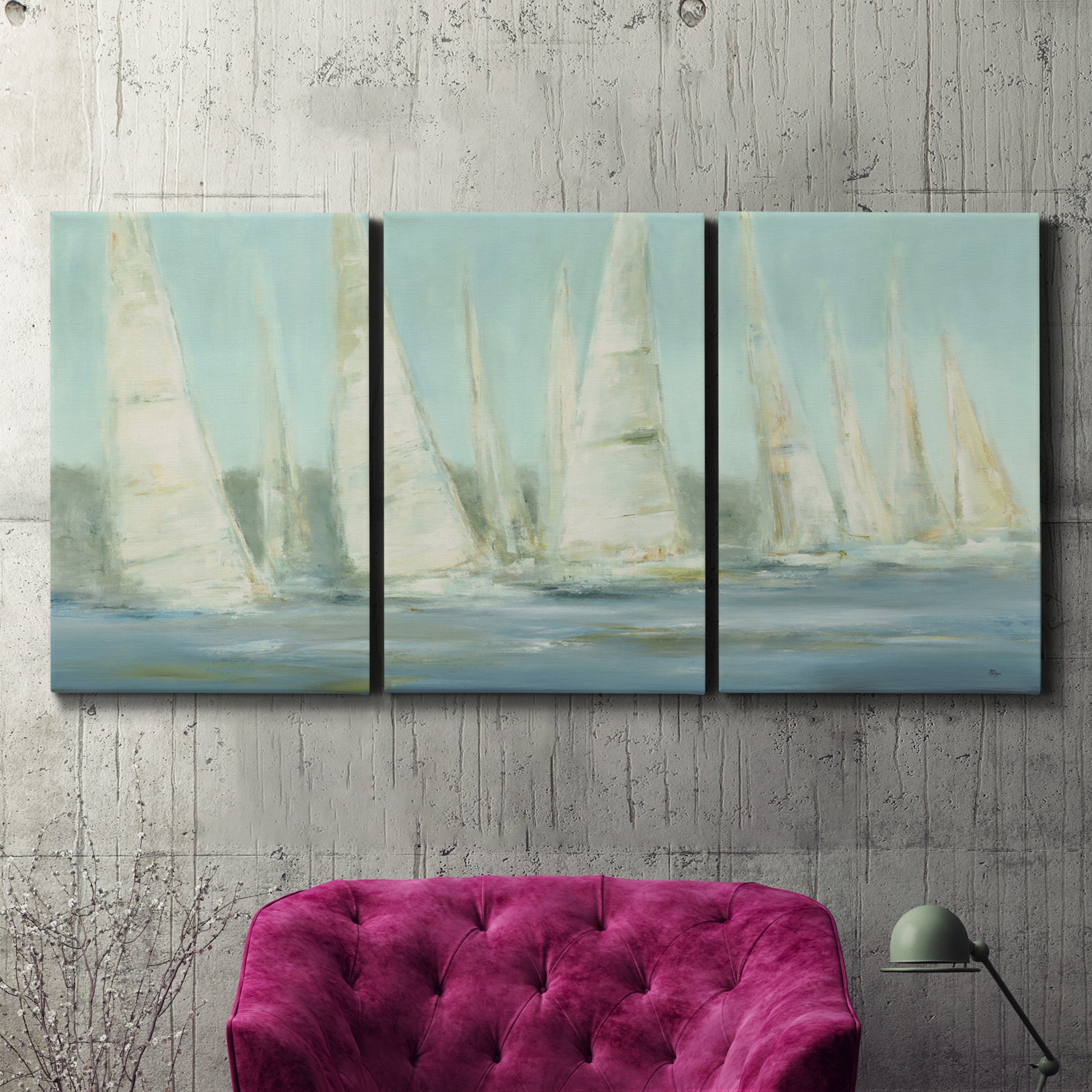 Three-panel canvas wall art featuring sailboats silhouetted at sunrise, displayed in a living room above a suede accent chair.