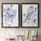 Set of two black barnwood framed canvas prints depicting two expressive watercolor botanical paintings featuring loose blue flowers and leafy branches above a sideboard in a cozy sitting room.