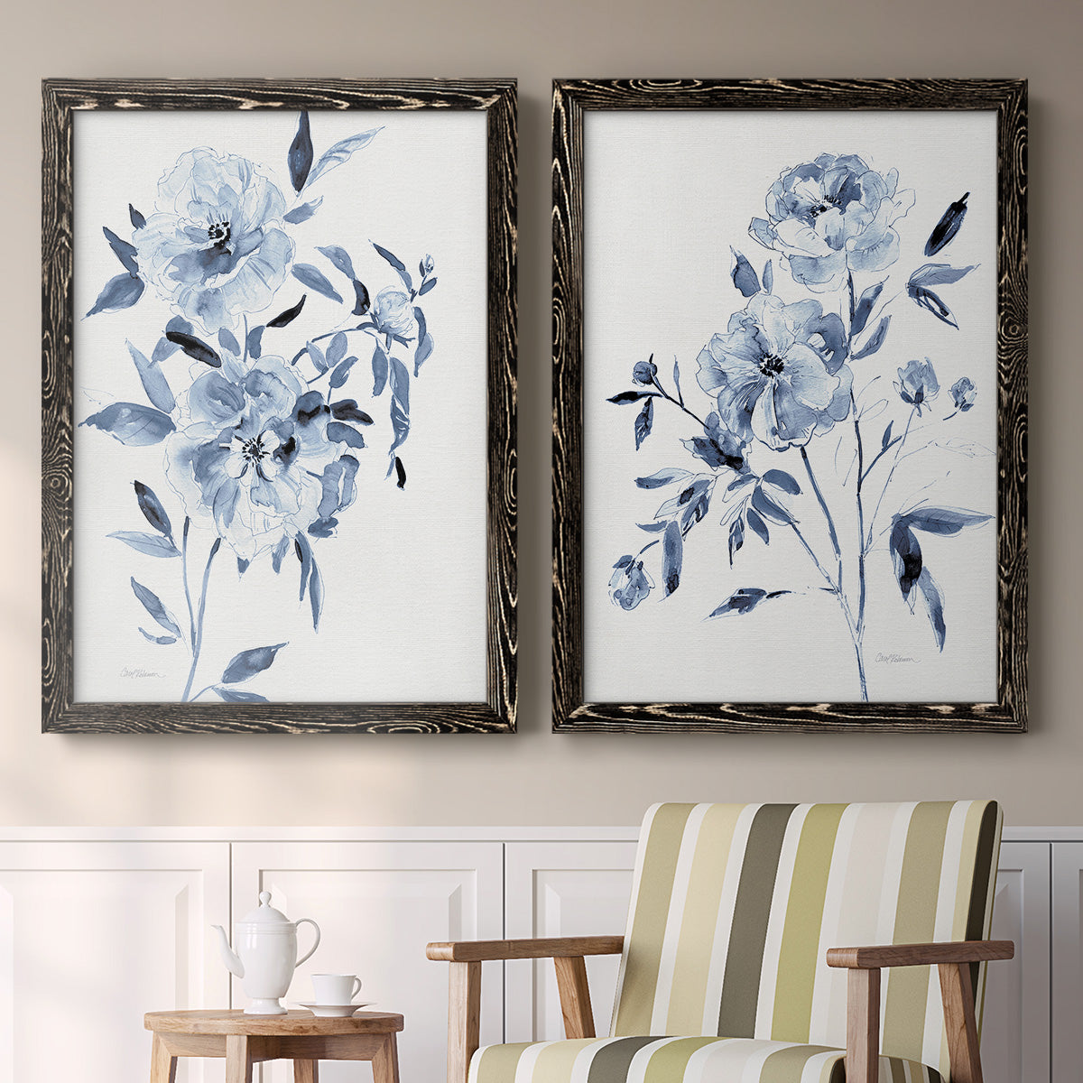 Set of two black barnwood framed canvas prints depicting two expressive watercolor botanical paintings featuring loose blue flowers and leafy branches above a sideboard in a cozy sitting room.