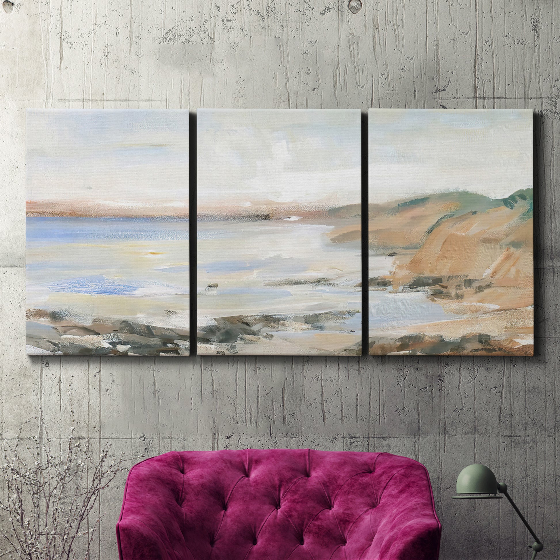 Three-panel canvas wall art featuring coastal shoreline landscape study, displayed in a living room above a suede accent chair.