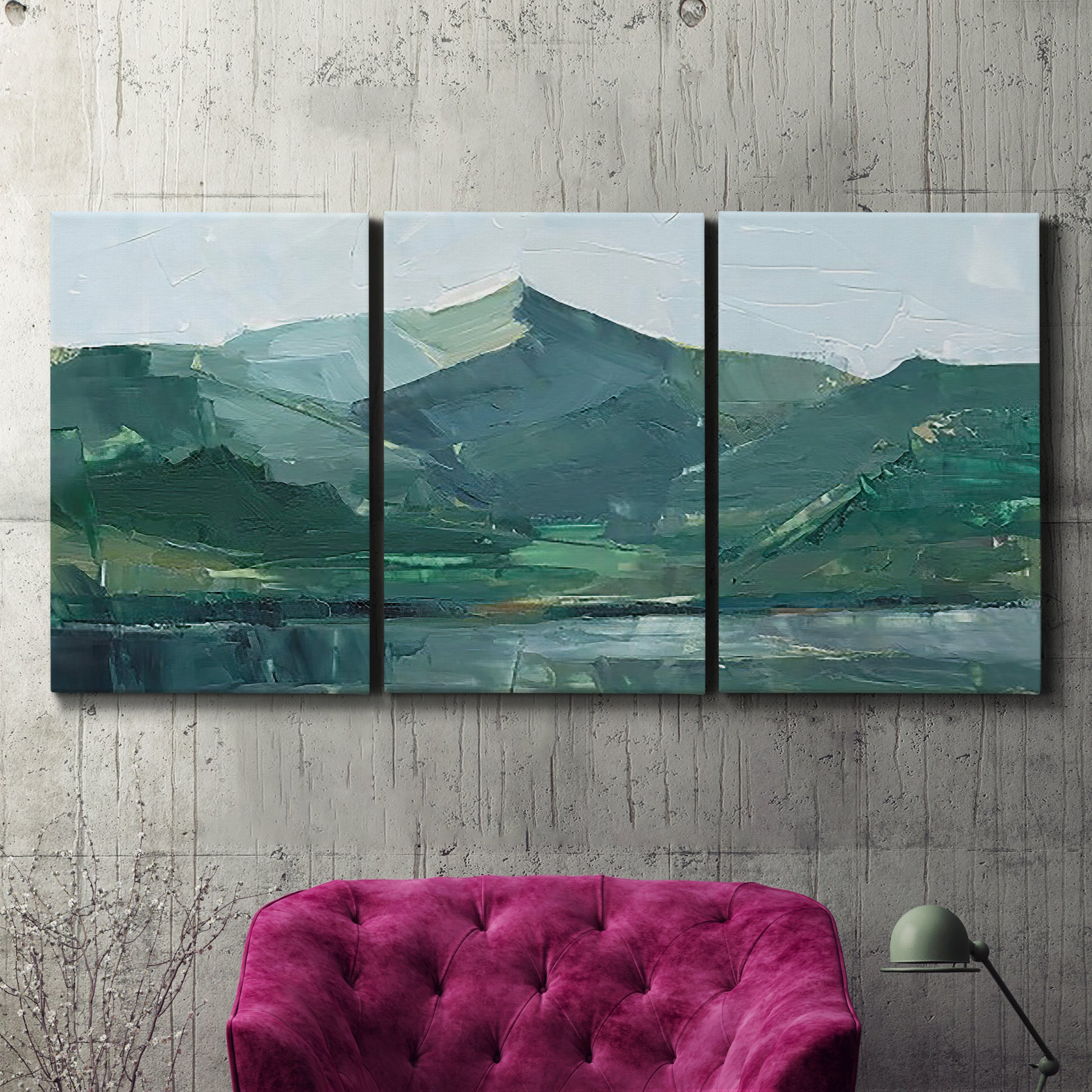 Three-panel canvas wall art featuring muted mountain range in grey tones, displayed in a living room above a suede accent chair.