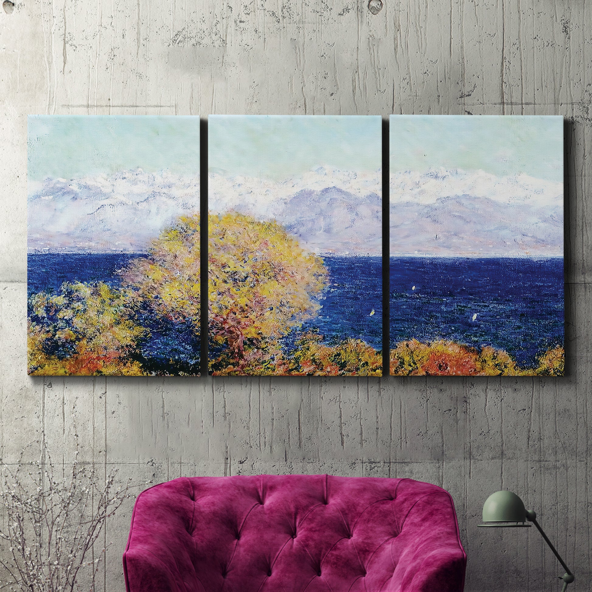 Three-panel canvas wall art featuring mediterranean coastline with headland, displayed in a living room above a suede accent chair.