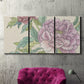 Three-panel canvas wall art featuring soft pink peony blossoms, displayed in a living room above a suede accent chair.