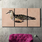 Three-panel canvas wall art featuring coastal bird illustration, displayed in a living room above a suede accent chair.