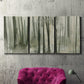 Three-panel canvas wall art featuring wooded forest path watercolor, displayed in a living room above a suede accent chair.