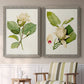 Set of two gray barnwood framed canvas prints depicting two traditional botanical paintings featuring white magnolia blossoms and glossy green leaves above a sideboard in a cozy sitting room.