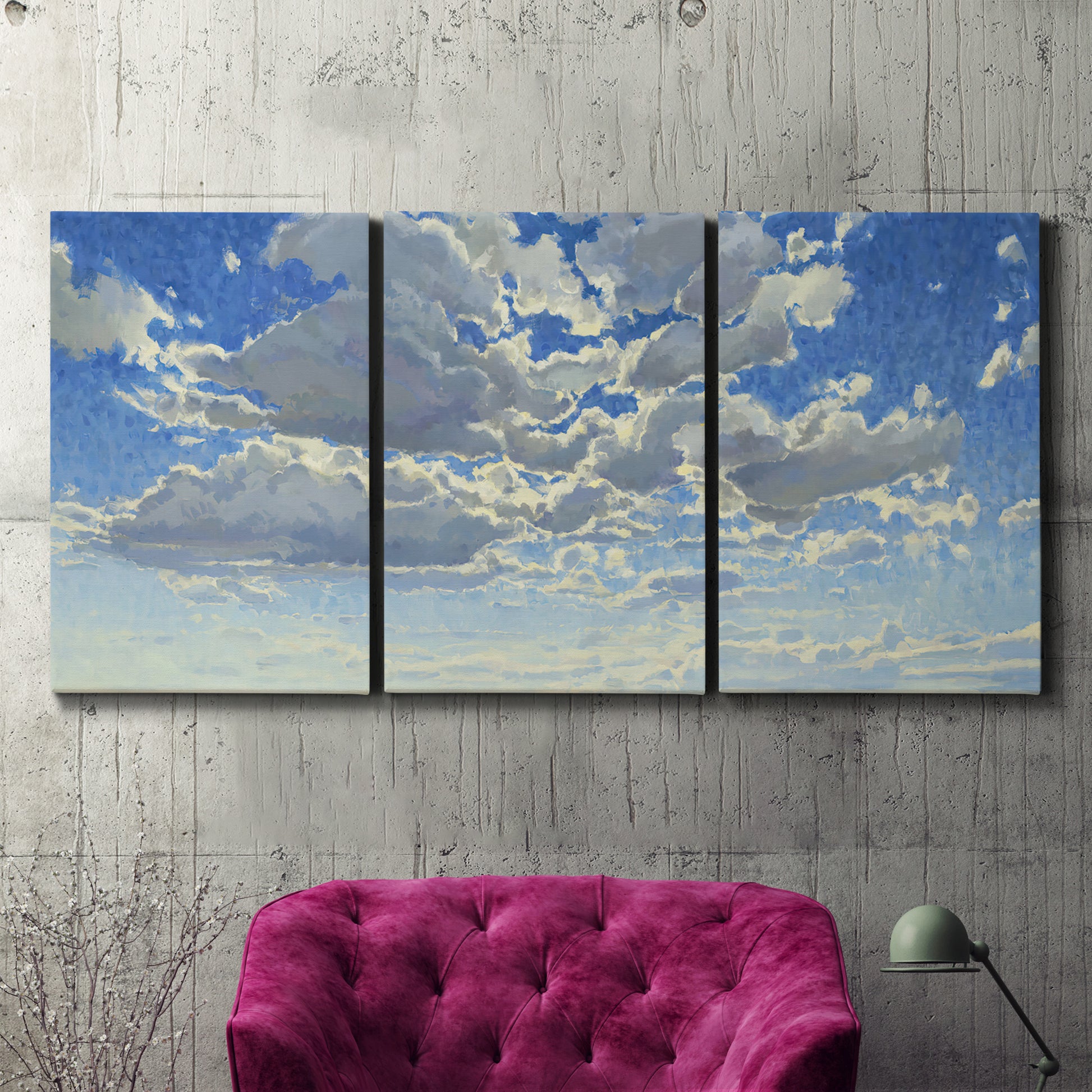 Three-panel canvas wall art featuring whimsical cloud filled sky landscape, displayed in a living room above a suede accent chair.