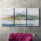 Three-panel canvas wall art featuring flowing blue abstract watercolor, displayed in a living room above a suede accent chair.