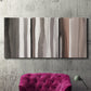 Three-panel canvas wall art featuring riverbank landscape with reflections, displayed in a living room above a suede accent chair.