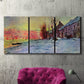 Three-panel canvas wall art featuring river view beneath cloudy sky, displayed in a living room above a suede accent chair.