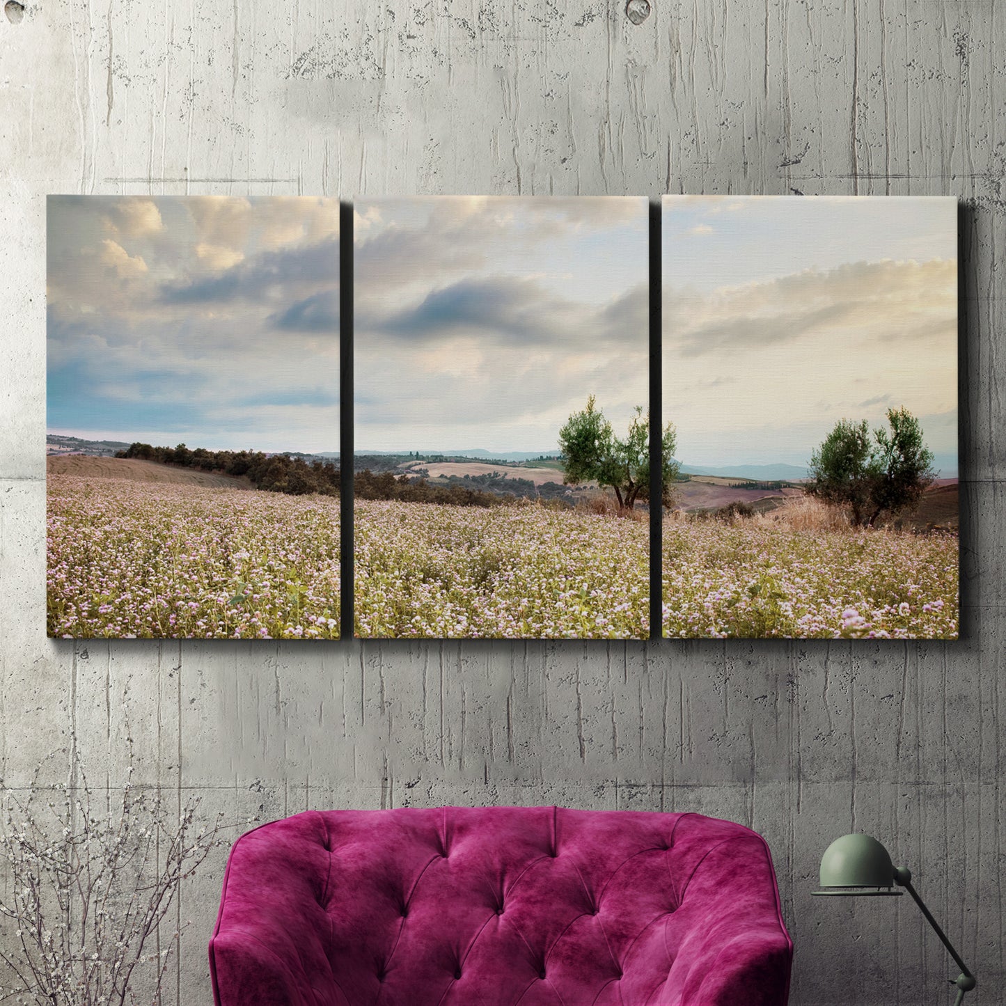 Three-panel canvas wall art featuring wildflowers across tuscan landscape, displayed in a living room above a suede accent chair.