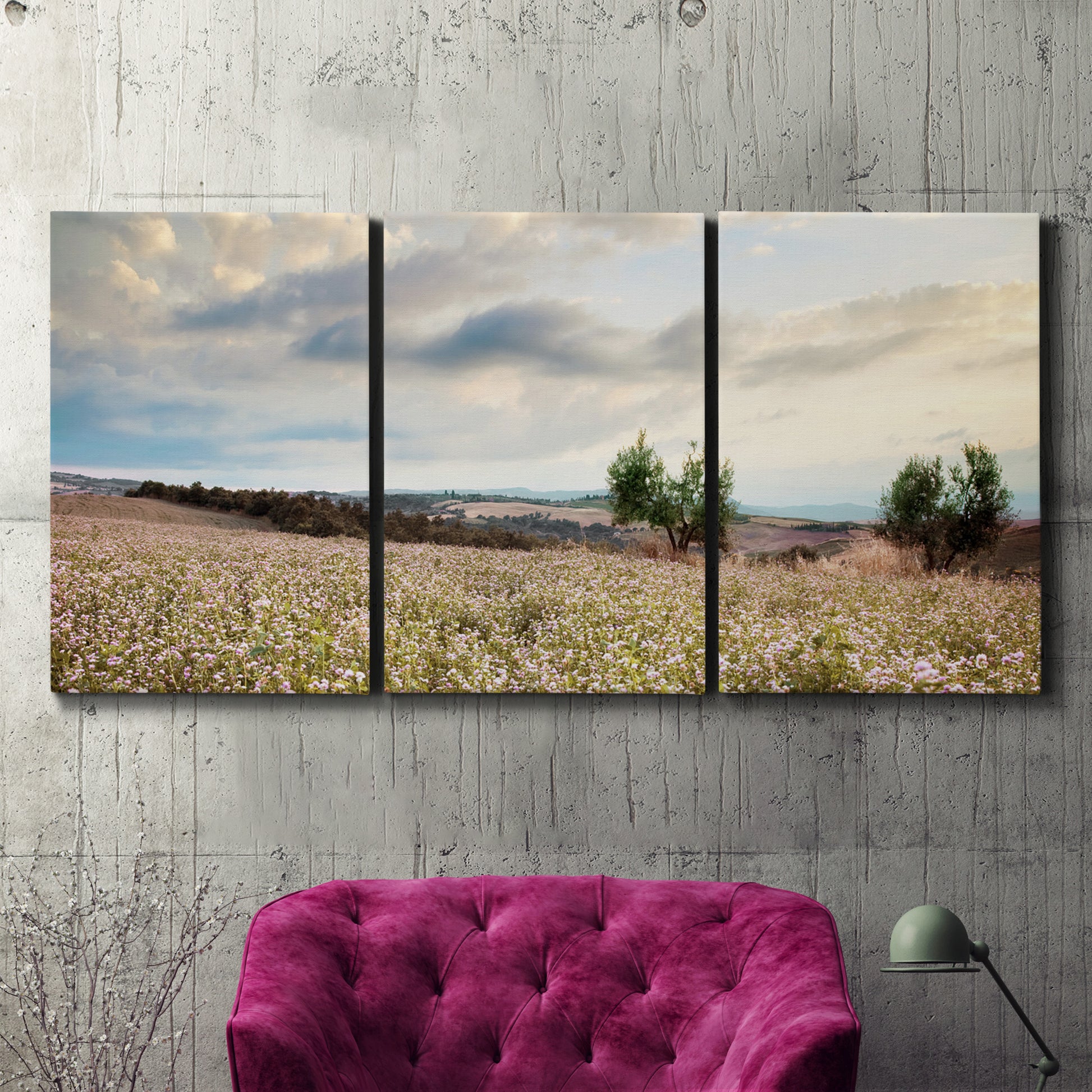 Three-panel canvas wall art featuring wildflowers across tuscan landscape, displayed in a living room above a suede accent chair.