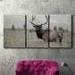 Three-panel canvas wall art featuring elk standing in open grassland, displayed in a living room above a suede accent chair.