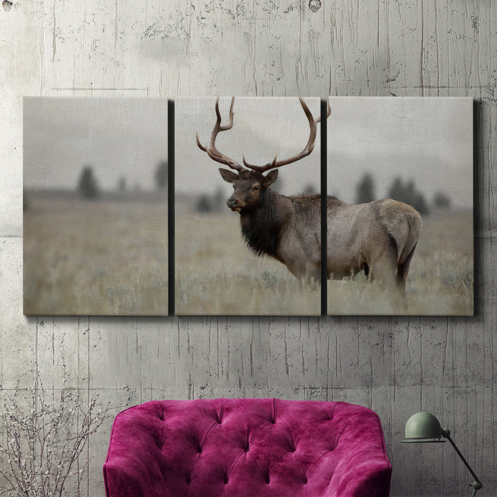 Three-panel canvas wall art featuring elk standing in open grassland, displayed in a living room above a suede accent chair.