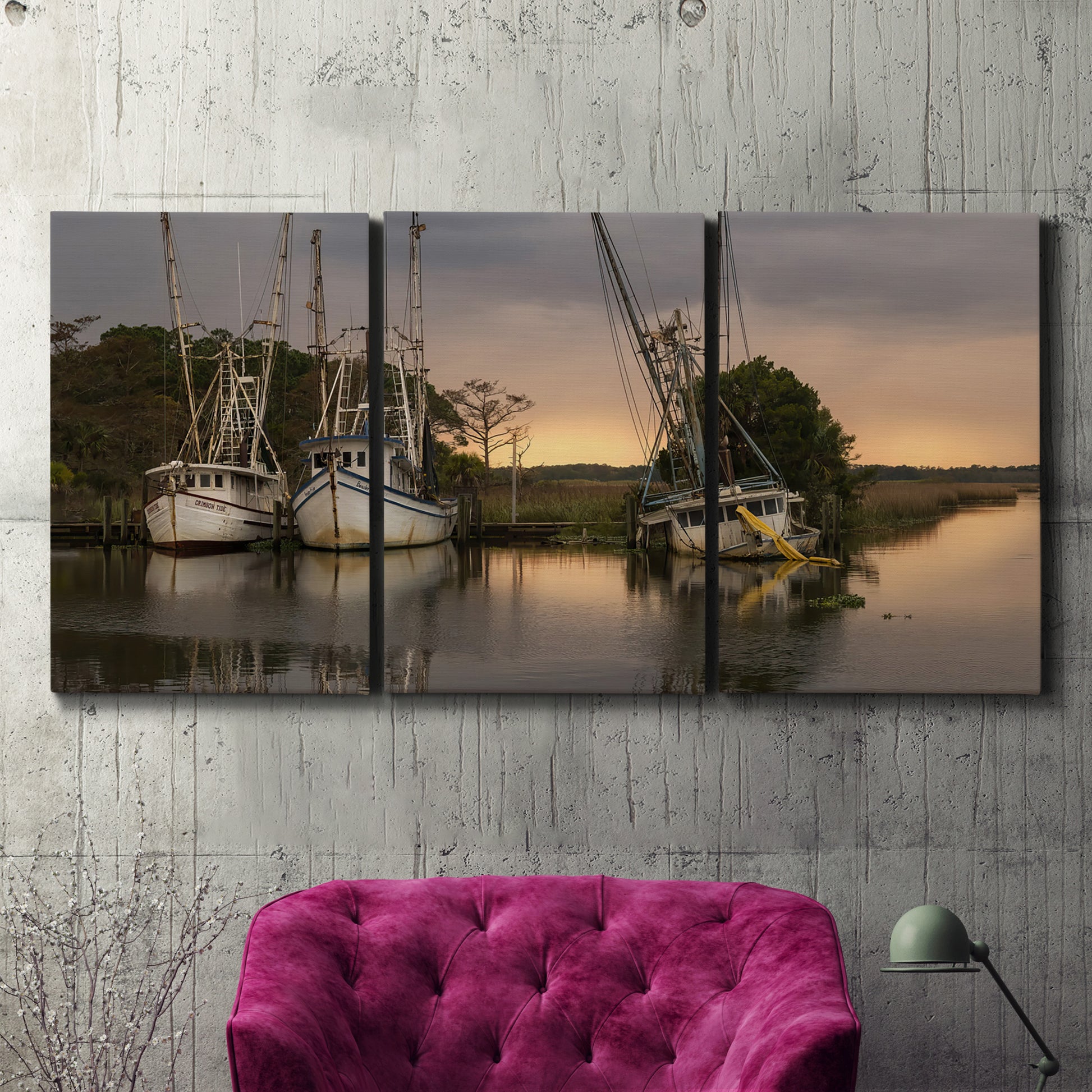 Three-panel canvas wall art featuring fishing trawlers on working harbor, displayed in a living room above a suede accent chair.
