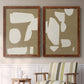 Set of two maple barnwood framed canvas prints depicting two bold minimalist shape abstracts featuring irregular white cutout-like shapes on taupe grounds above a sideboard in a cozy sitting room.