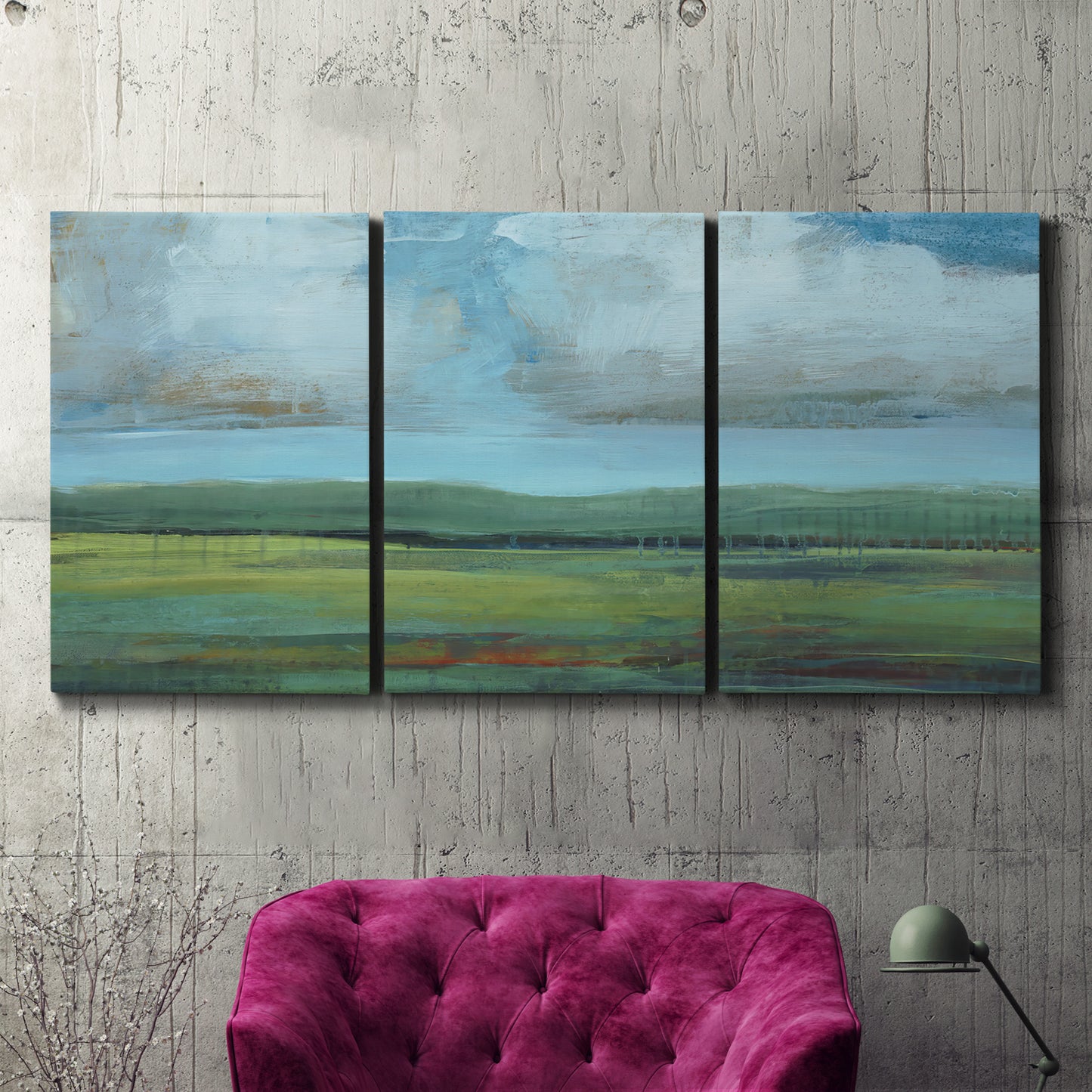 Three-panel canvas wall art featuring wide valley landscape with rolling hills, displayed in a living room above a suede accent chair.