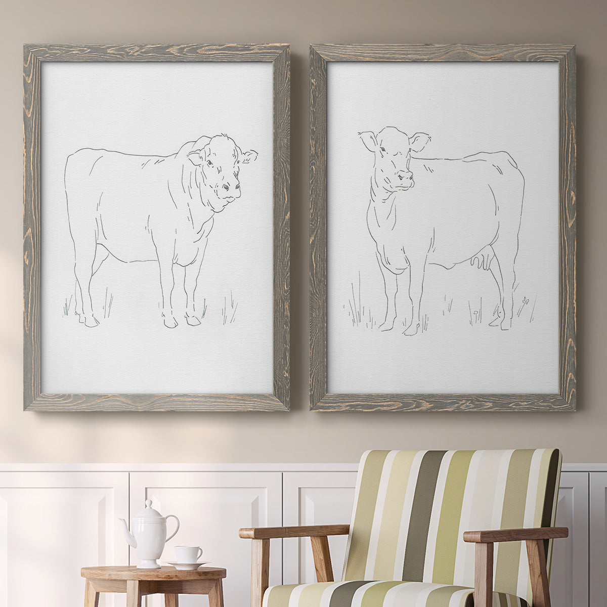 Set of two gray barnwood framed canvas prints depicting two minimalist livestock sketches featuring simple contour drawings of standing cows above a sideboard in a cozy sitting room.