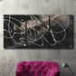 Three-panel canvas wall art featuring dark swirling abstract motion, displayed in a living room above a suede accent chair.