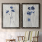Set of two black barnwood framed canvas prints depicting two rustic monochrome botanical paintings featuring blue wildflower stems on weathered neutral paper above a sideboard in a cozy sitting room.