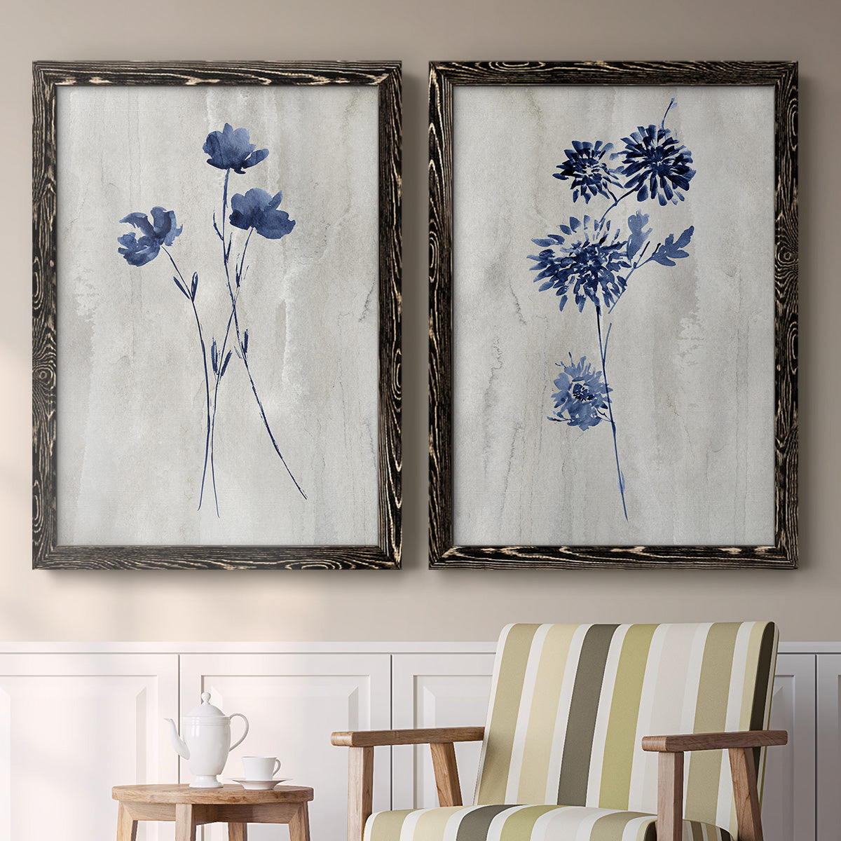 Set of two black barnwood framed canvas prints depicting two rustic monochrome botanical paintings featuring blue wildflower stems on weathered neutral paper above a sideboard in a cozy sitting room.