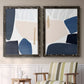 Set of two black barnwood framed canvas prints depicting two minimalist color-block abstracts featuring large navy cream and beige organic geometric shapes above a sideboard in a cozy sitting room.