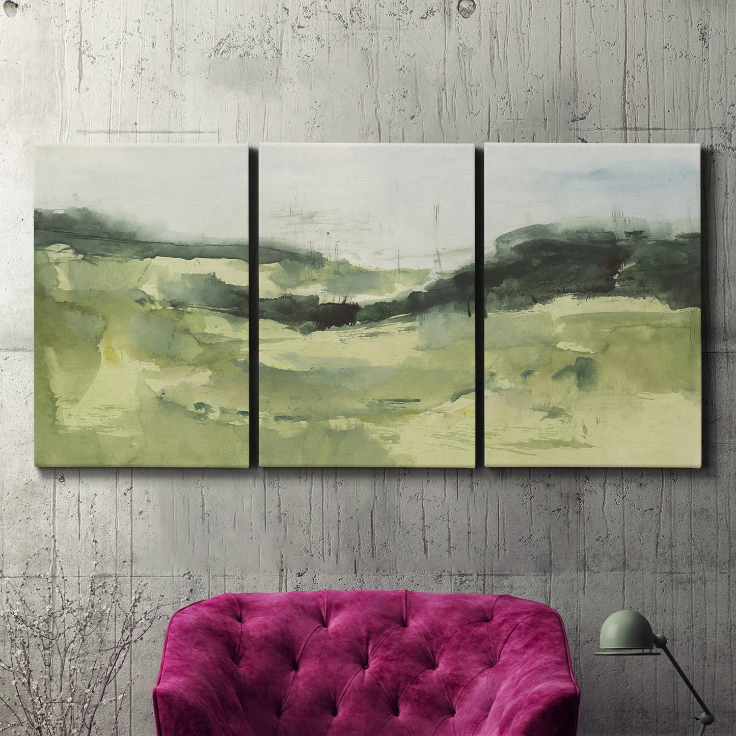 Three-panel canvas wall art featuring rolling hillside countryside landscape, displayed in a living room above a suede accent chair.