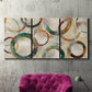 Three-panel canvas wall art featuring geometric circular abstract design, displayed in a living room above a suede accent chair.