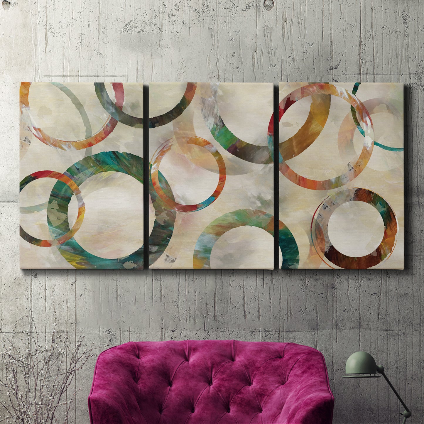 Three-panel canvas wall art featuring geometric circular abstract design, displayed in a living room above a suede accent chair.
