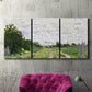 Three-panel canvas wall art featuring spring landscape with blossoming trees, displayed in a living room above a suede accent chair.