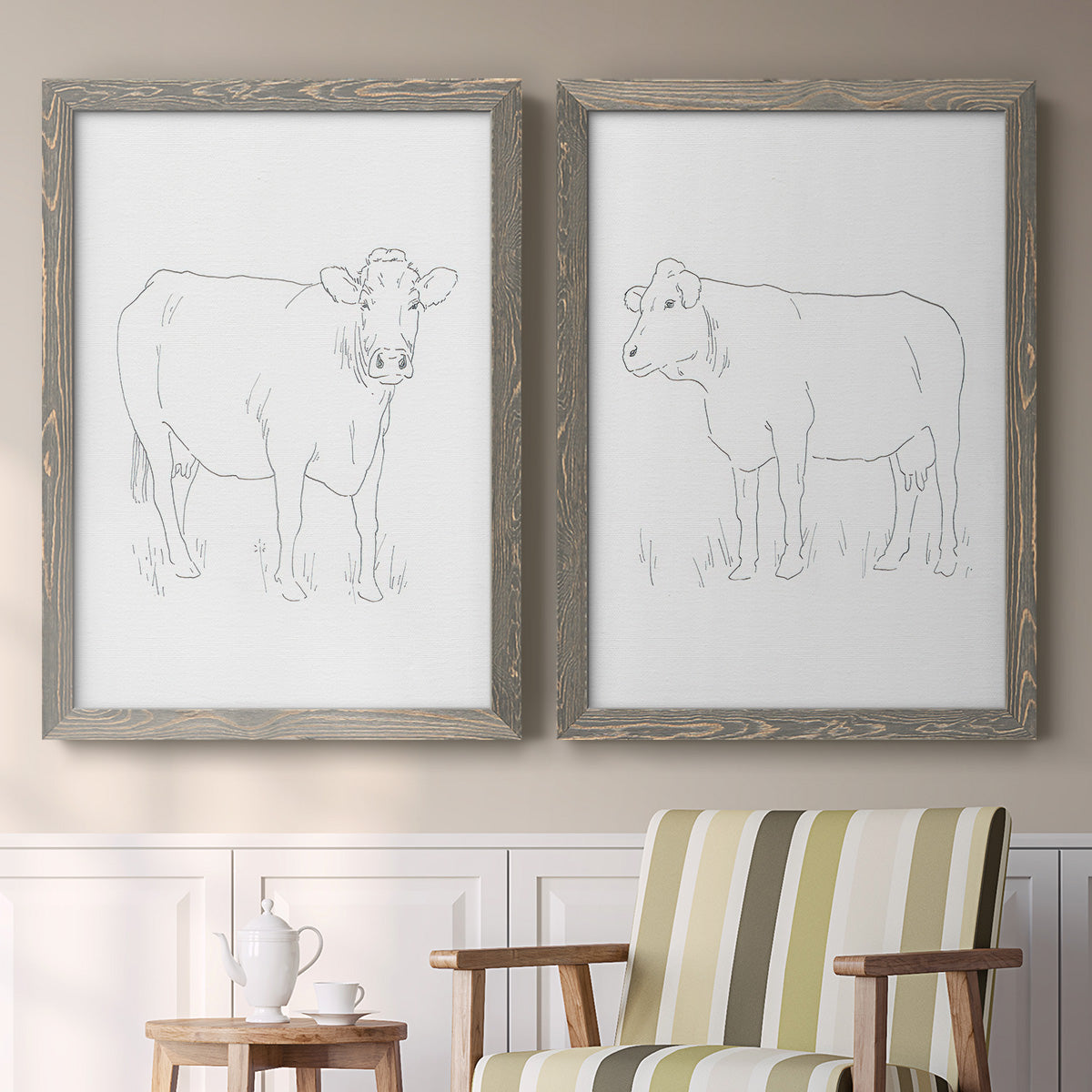Set of two gray barnwood framed canvas prints depicting two minimalist livestock sketches featuring simple contour drawings of standing cows above a sideboard in a cozy sitting room.