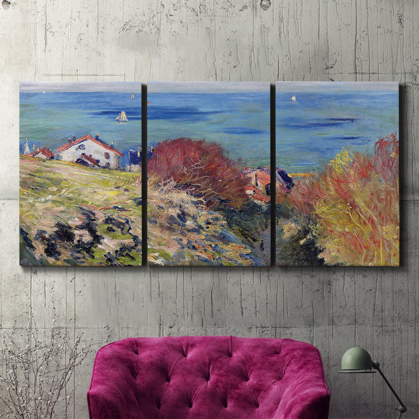 Three-panel canvas wall art featuring coastal village shoreline landscape, displayed in a living room above a suede accent chair.