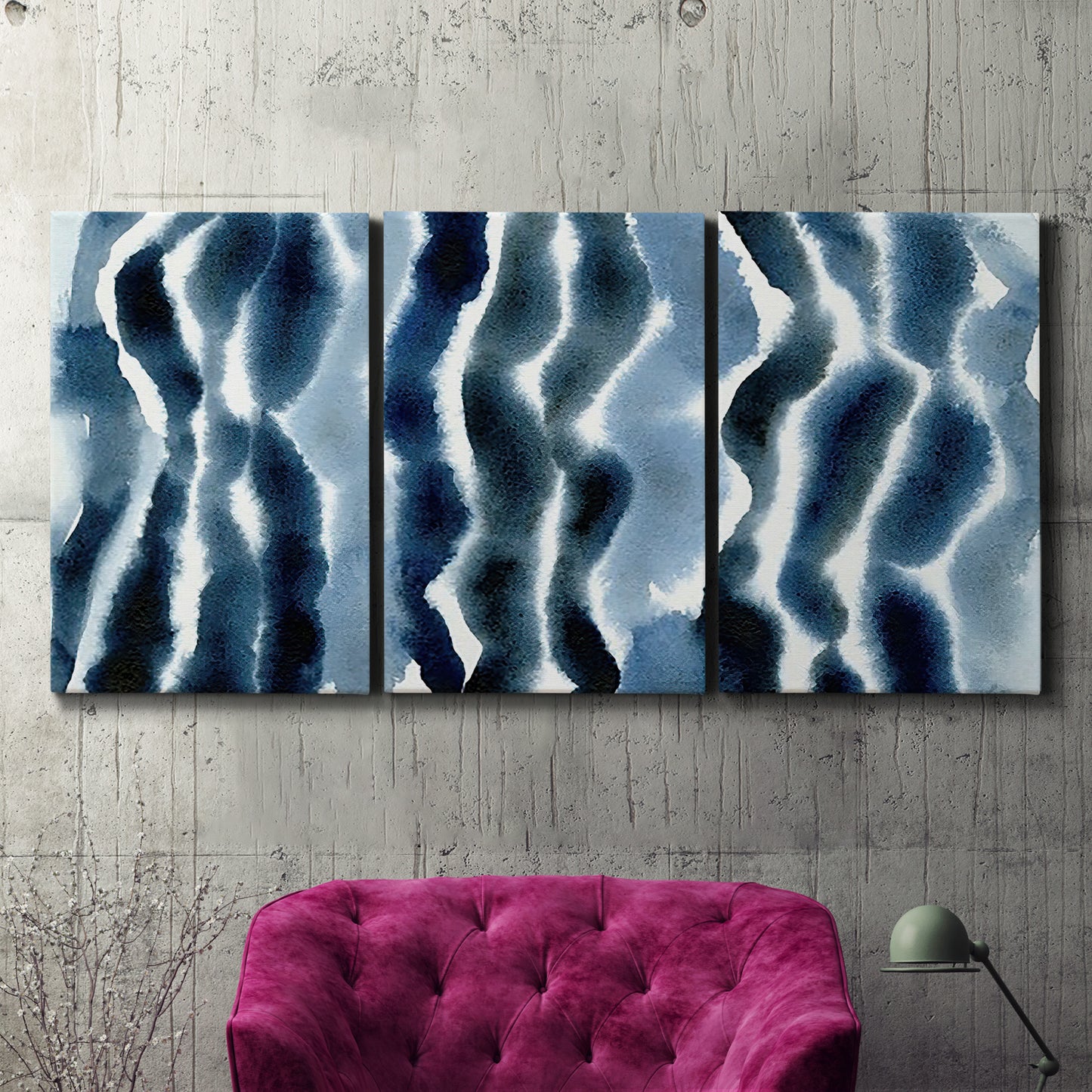 Three-panel canvas wall art featuring flowing blue watercolor wave forms, displayed in a living room above a suede accent chair.