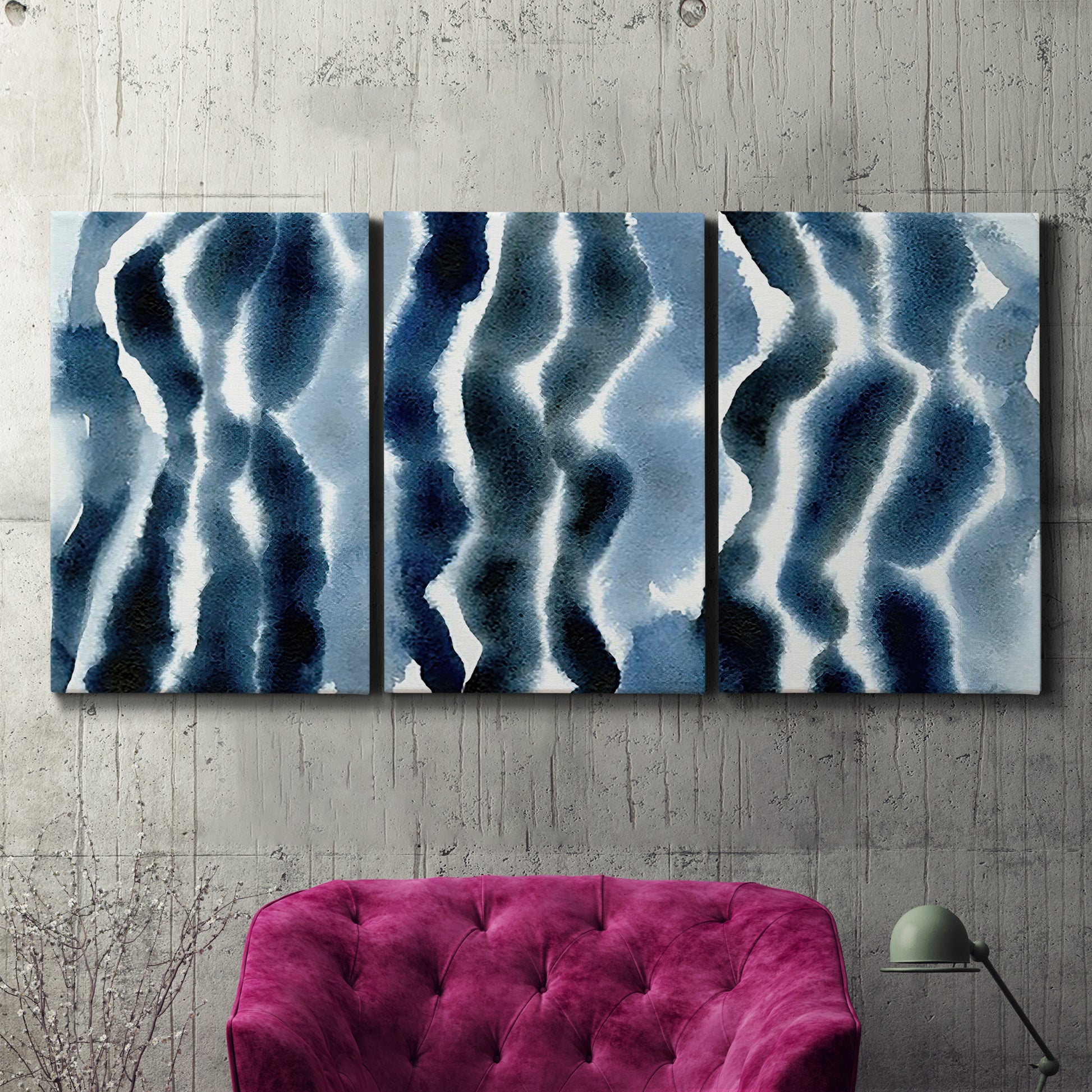 Three-panel canvas wall art featuring flowing blue watercolor wave forms, displayed in a living room above a suede accent chair.