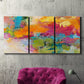 Three-panel canvas wall art featuring expressive abstract sunset tones, displayed in a living room above a suede accent chair.