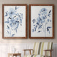 Set of two maple barnwood framed canvas prints depicting two expressive watercolor botanical paintings featuring loose blue flowers and leafy branches above a sideboard in a cozy sitting room.