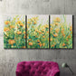Three-panel canvas wall art featuring colorful garden flowers in bloom, displayed in a living room above a suede accent chair.