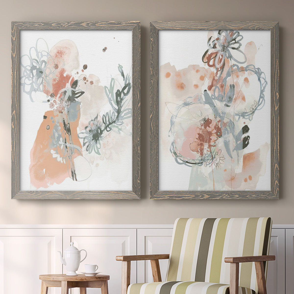 Set of two gray barnwood framed canvas prints depicting two abstract watercolor botanicals featuring loose blush gray and coral floral gestures above a sideboard in a cozy sitting room.