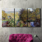 Three-panel canvas wall art featuring garden corner with flowering trees, displayed in a living room above a suede accent chair.