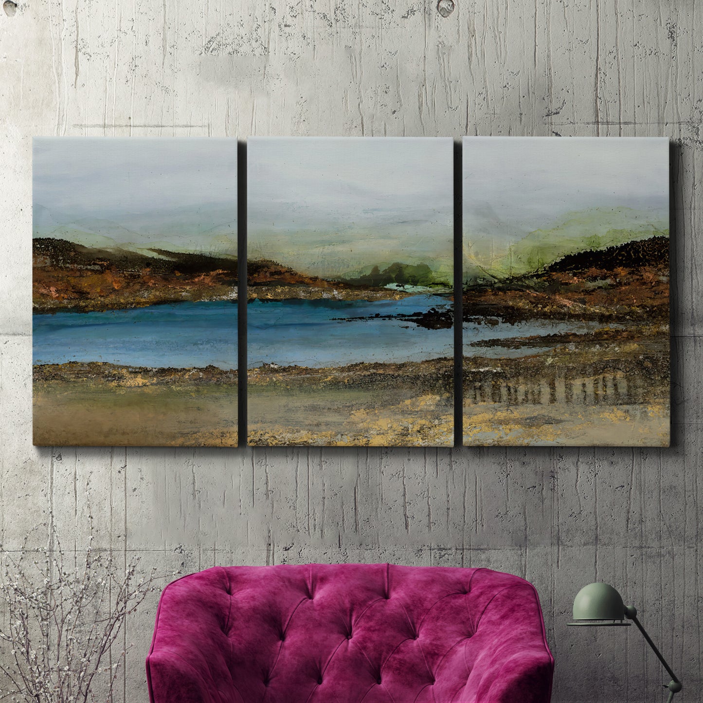 Three-panel canvas wall art featuring peaceful lakeside shoreline landscape, displayed in a living room above a suede accent chair.