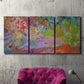 Three-panel canvas wall art featuring vibrant abstract with dramatic motion, displayed in a living room above a suede accent chair.