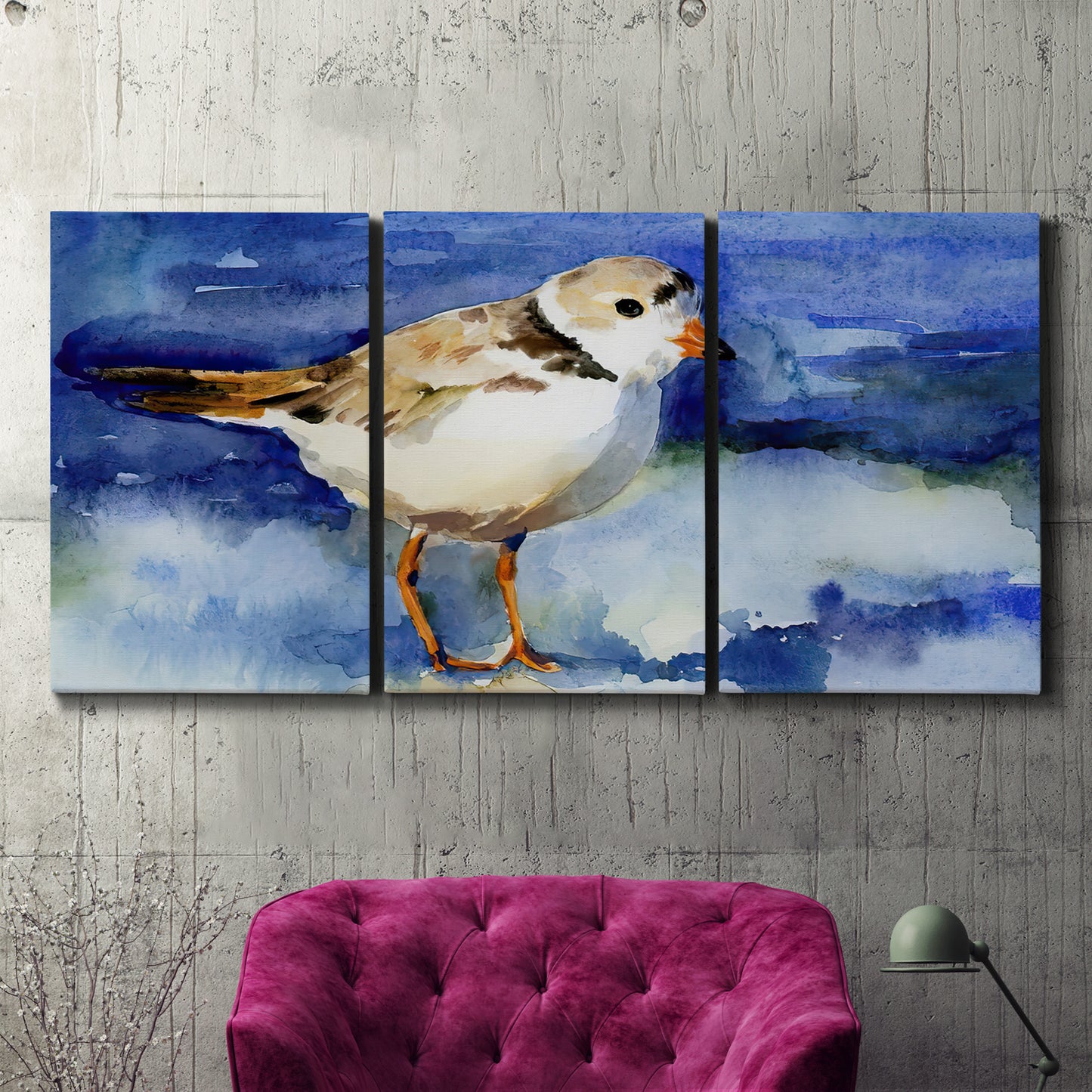 Three-panel canvas wall art featuring shorebirds standing in shallow water, displayed in a living room above a suede accent chair.