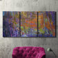 Three-panel canvas wall art featuring abstract rainfall with butterfly forms, displayed in a living room above a suede accent chair.