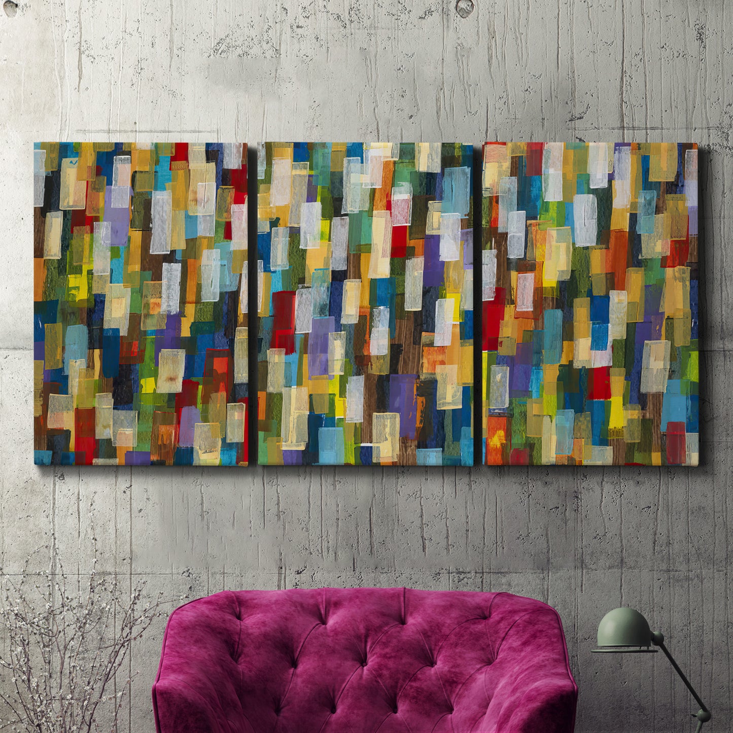 Three-panel canvas wall art featuring colorful confetti style abstraction, displayed in a living room above a suede accent chair.