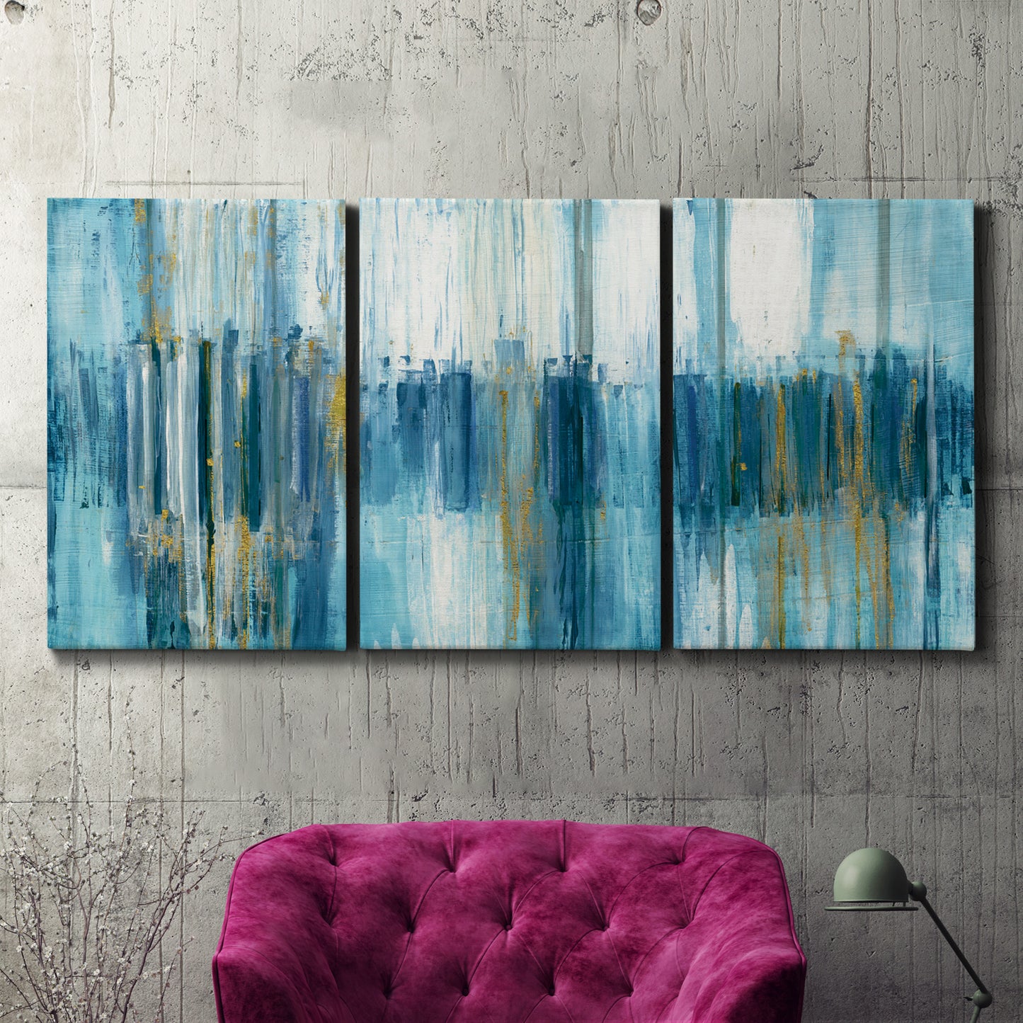 Three-panel canvas wall art featuring layered abstract earth tones, displayed in a living room above a suede accent chair.