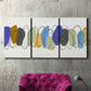 Three-panel canvas wall art featuring minimalist geometric abstract spacing, displayed in a living room above a suede accent chair.