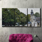 Three-panel canvas wall art featuring chapel building in rural setting, displayed in a living room above a suede accent chair.